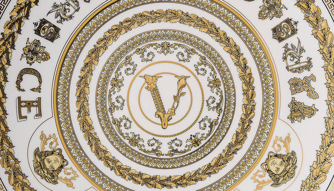 Decorative plate with gold and black designs on a white background