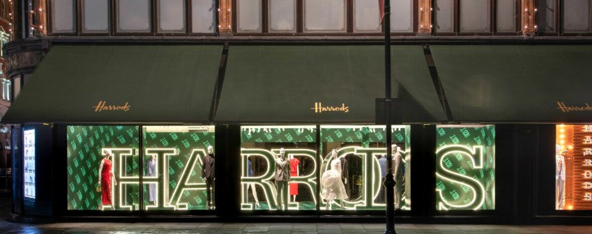 Harrods store front with illuminated sign at night