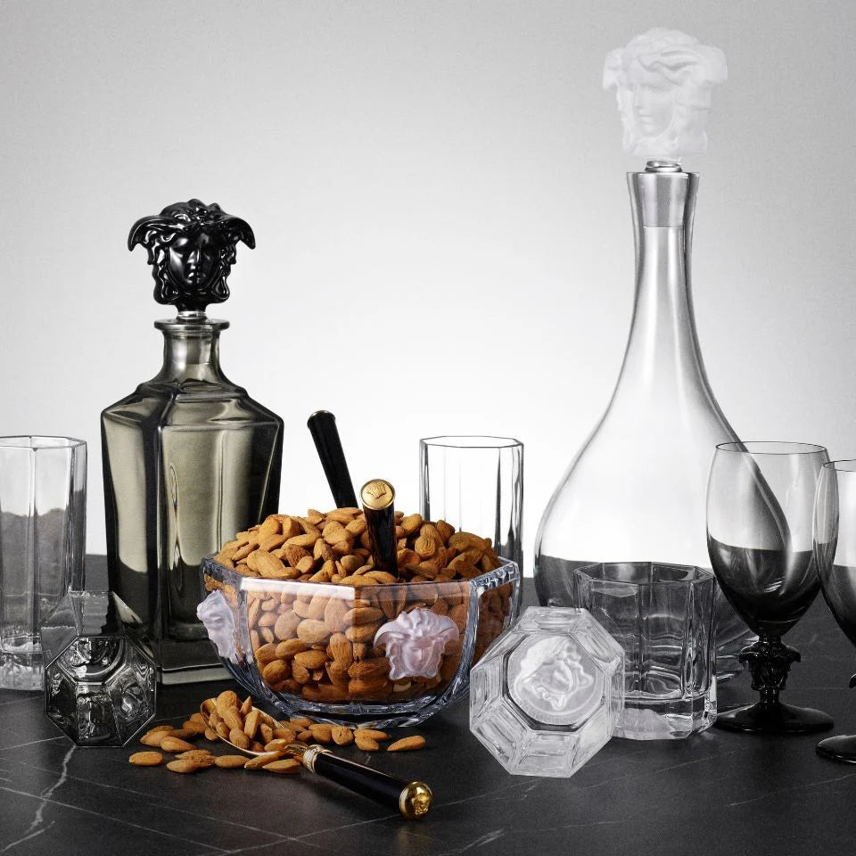 Decorative glassware with a bowl of nuts on a dark surface