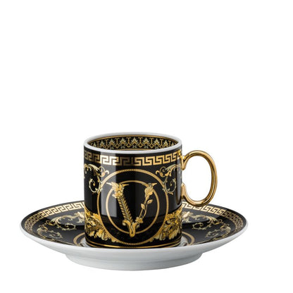 Decorative coffee cup and saucer with gold and black design on a white background