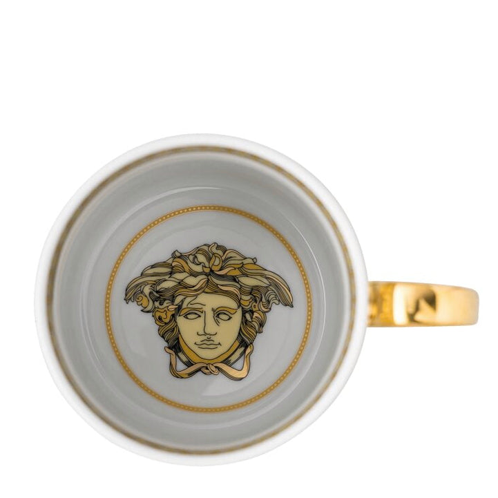 White cup with gold accents and a face design on a white background